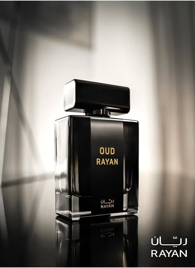 Black perfume bottle labeled 'Oud Rayan' on a reflective surface with a blurred background