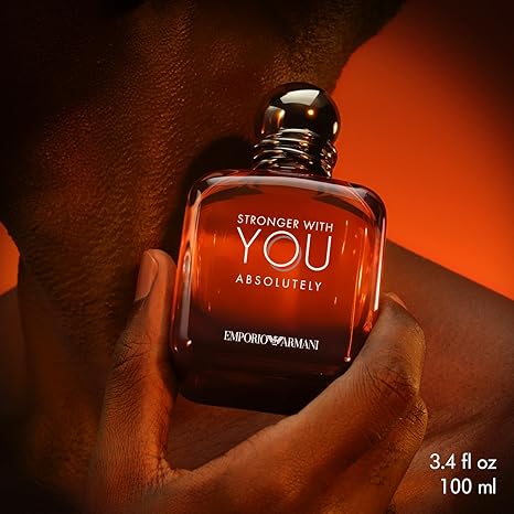 Emporio Armani perfume bottle held in a hand with an orange background