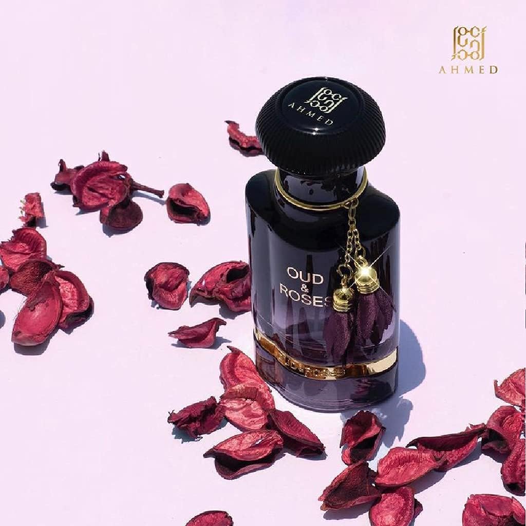 Perfume bottle labeled 'Oud & Rose' by AHMED with dried rose petals on a light pink background